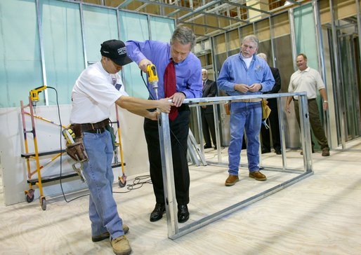 President George W. Bush uses a drill to connect a metal wall frame during a tour of the Carpenters Training Center in Phoenix, Ariz., Friday, March 26, 2004. White House photo by Eric Draper.