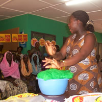 A facilitator demonstrating treatment with insecticide of bednets to a group of women